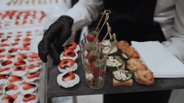The waiter puts on a tray of canapes with cherry and strawberry. Catering