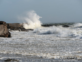 Wave crashing onto rocks on a  beach creating splash.