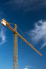 isolated yellow construction tower crane ground view tall sky background