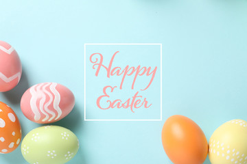Flat lay composition of colorful painted eggs and text Happy Easter on color background