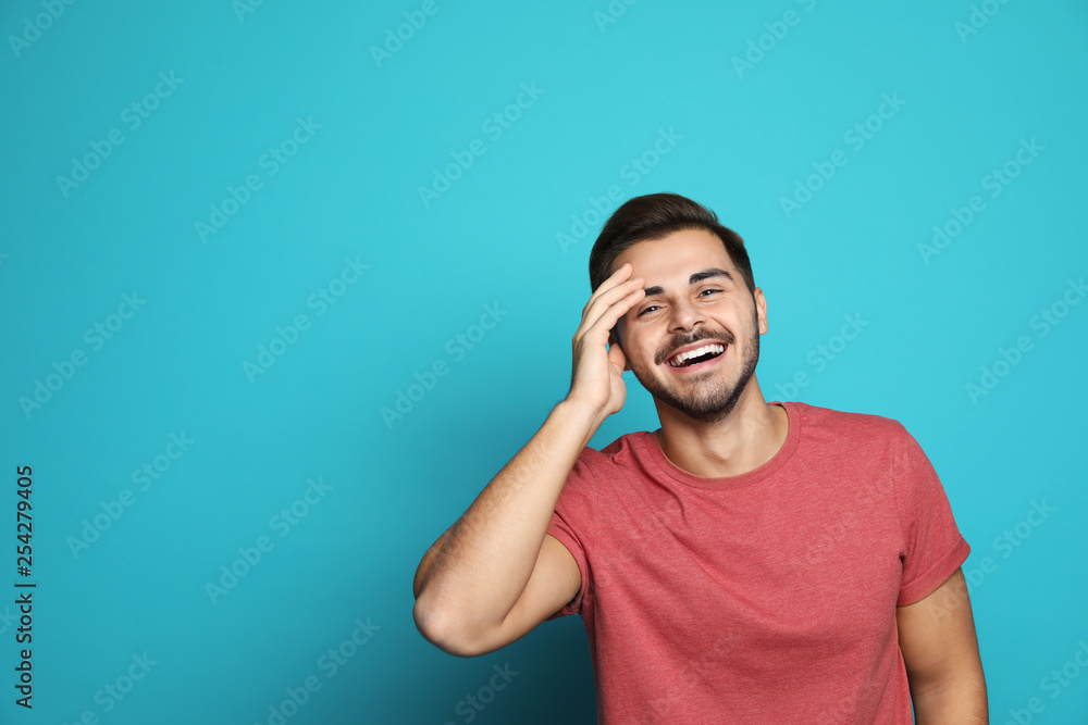 Poster Handsome young man laughing against color background. Space for text