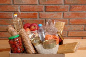 Donation box with food on table near brick wall