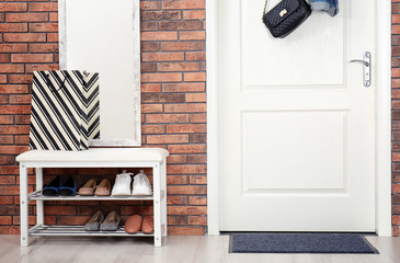 Hallway interior with shoe rack, mirror and mat near door