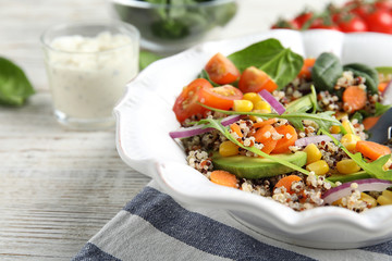 Healthy quinoa salad with vegetables in plate on table, closeup. Space for text