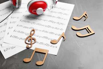 Music notes and headphones on grey table