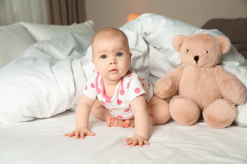 Cute baby girl with toy on bed at home. Bedtime schedule