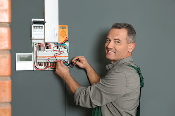 Professional electrician with tester checking voltage indoors