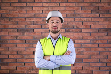 Male industrial engineer in uniform on brick wall background. Safety equipment