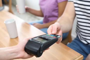 Client using credit card machine for non cash payment indoors, closeup