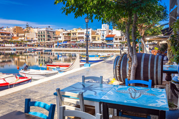 The lake Voulismeni in Agios Nikolaos,  a picturesque coastal town with colorful buildings around...