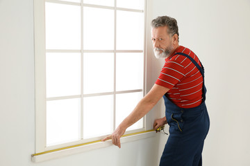 Service man measuring window for installation indoors