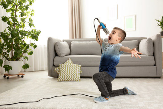 Cute funny boy with microphone in living room