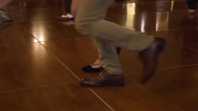 Vintage couple dances across the wooden floor displaying their skill through old timey dance moves.