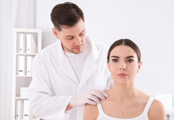 Fototapeta premium Doctor examining patient in clinic. Visiting dermatologist
