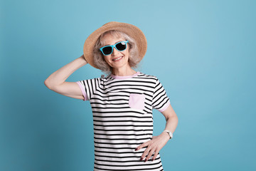 Portrait of mature woman in hipster outfit on color background