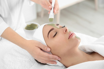 Fototapeta na wymiar Cosmetologist applying mask on client's face in spa salon