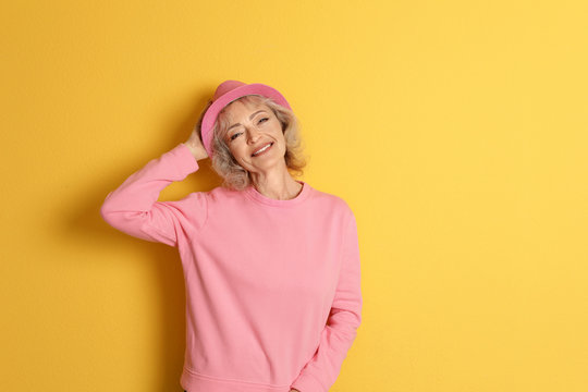 Portrait of mature woman in hipster outfit on color background. Space for text