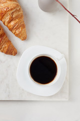 Croissants and a cup of coffee on the white marble board