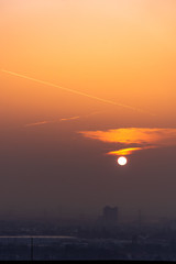 Obraz premium Power lines in city on dawn. Silhouettes of urban buildings among smog on sunrise. Cables of high voltage on warm orange yellow sky