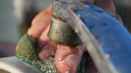 White cup is washed with a watercloth kept by a hand outdoors in summer