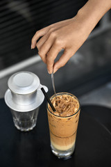 Girl stirs iced coffee drink with spoon in outdoor cafe