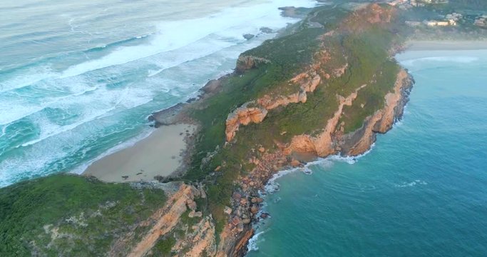 Aerial top down pan of Robberg Nature Reserve, a beautiful rock mountain landscape surrounded by blue ocean.