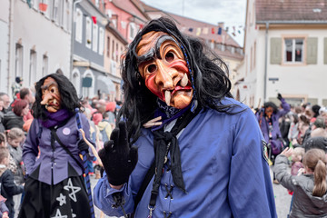 Funny witch with big teeth and long nose, waves with one hand.  Carnival in southern Germany - Black Forest.