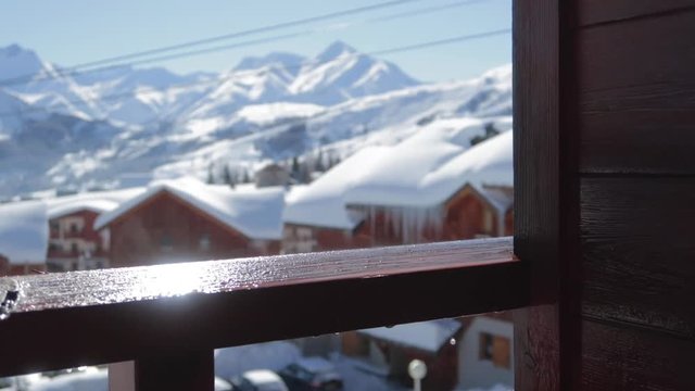 Water droplets falling onto wooden balcony ramp in a ski resort in winter