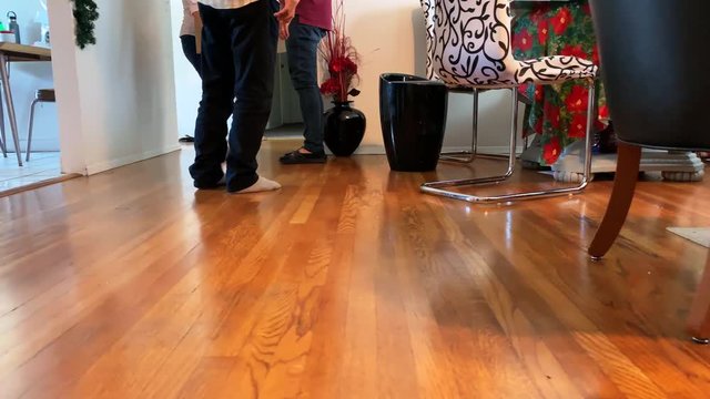Perspective tracking from right to left of people's feet in the living room working together.