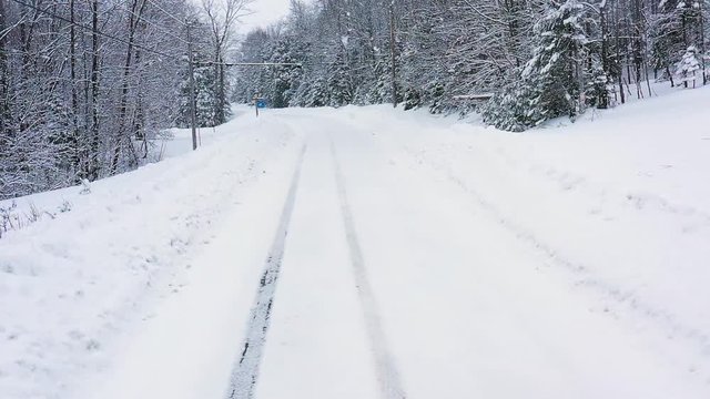 Flying just above a snow covered forest road during a snow storm AERIAL SLOW MOTION