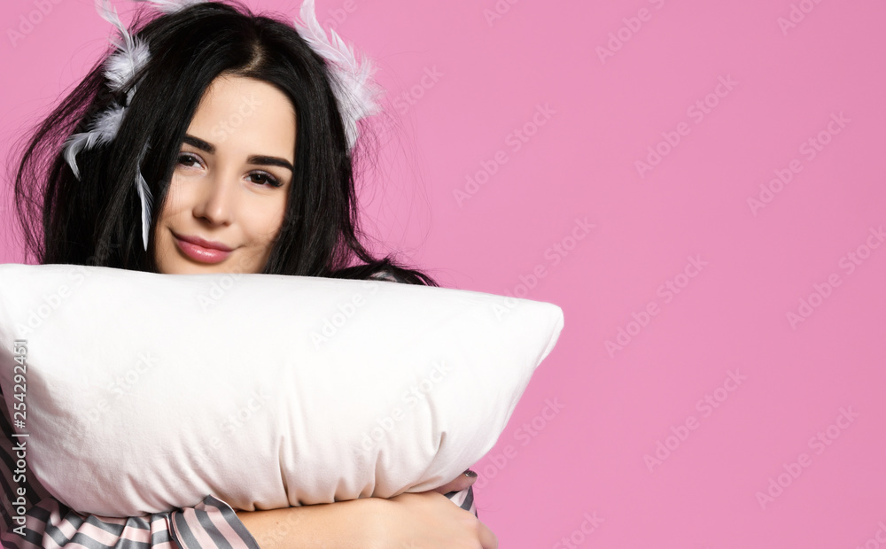 Wall mural Beautiful brunette girl just woke up with soft pillow feathers and sleepy mask bandage for sleep 