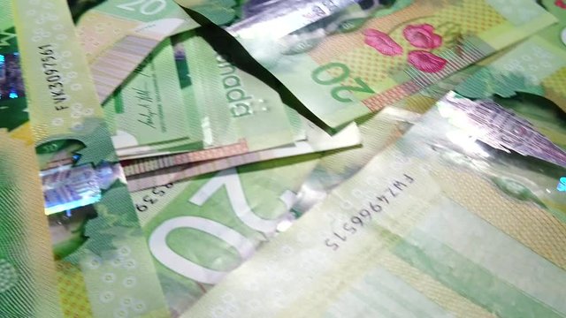 a huge pile of the Canadian twenty dollar bills in slow motion