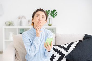 スマートフォンを見るシニア女性　考える
