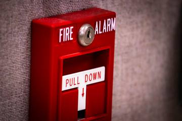 Manual fire alarm activation pull station on wall - signage reading: “FIRE ALARM” and “PULL...