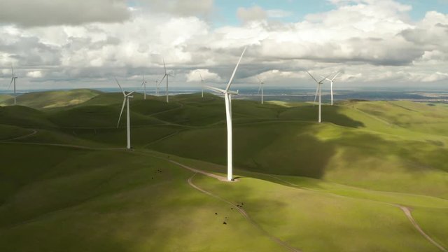 Rotating Drone shot of Wind Turbine at Altamont Pass on Vasco Road Highway with green rolling hills in California