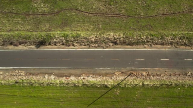 Overhead Shot of road leading to green rolling hills with blue sky and white clouds and trees on country road