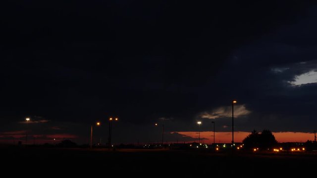Time-lapse shot of dramatic storm clouds after sunset with traffic and street lights.