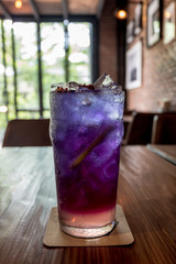 Close up glass of refreshing iced blueberry anchan and lemon soda on wooden table