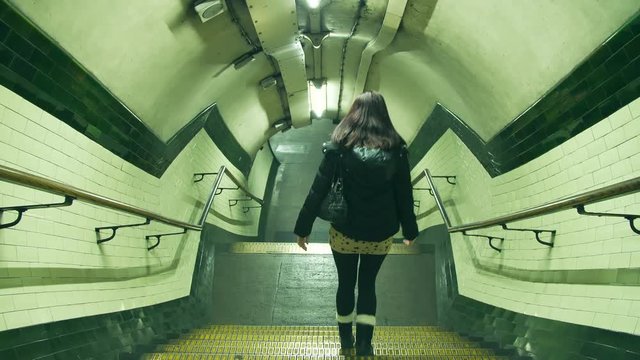 Woman walks alone down the stairs to the London Underground station