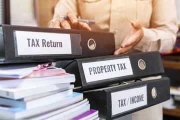 Tax return / property tax / Tax income word on folders stack label black binder on paperwork documents summary report in busy offices by manager checking. HR-human resources business accountancy ideas
