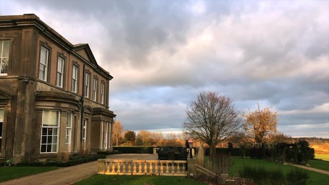 Grand Leicestershire Manor House side view with clouds blowing past and over courtyard and gardens
