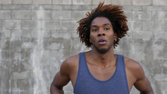 Man with wild hair enters frame and puts dreads into a ponytail.
