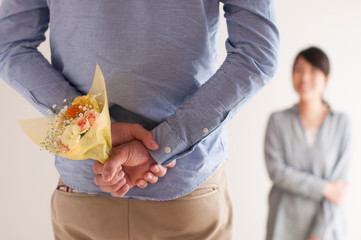 後ろに花束を隠す男性の手元