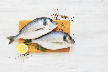 Raw fresh dorada fish with spices on wooden cutting board. Healthy food concept. Top view, copy space.