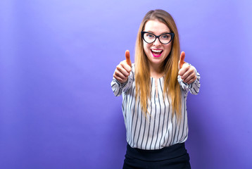 Fototapeta premium Happy young woman giving thumbs up on a solid background