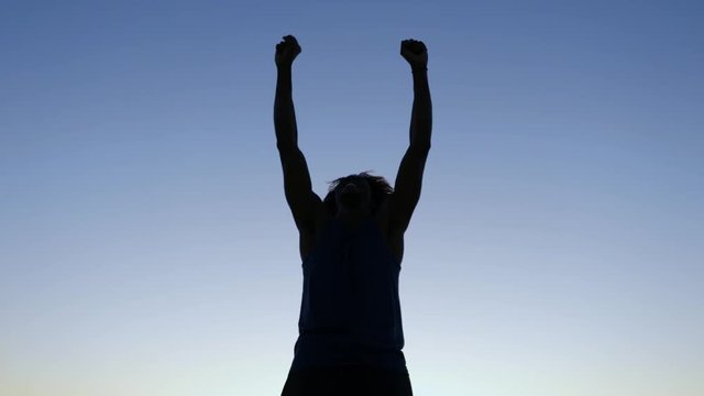 Silhouette of a victorious man at sunset.