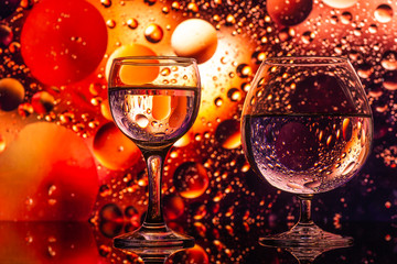 transparent glasses with water with oily drops on colorful background 