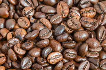 Macro detail of brown roasted coffee beans lying on a heap.