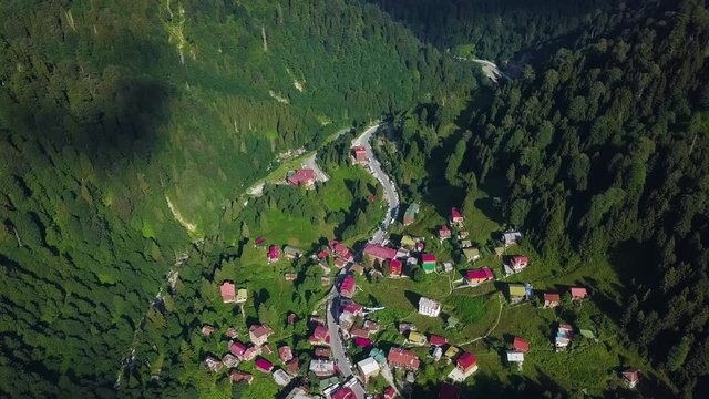 4K aerial bird look drone shot in slow motion, flying over Ayder Plateau, authentic settling between green epic mountains, sunny weather, in Ayder Highland, Rize Province, Turkey