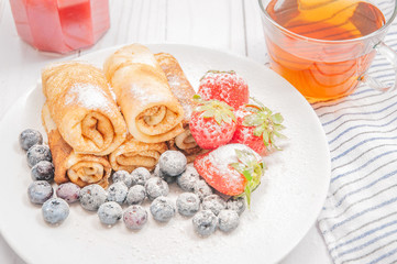 Healthy breakfast. Black tea and pancakes rolls with fresh berries and chocolate
